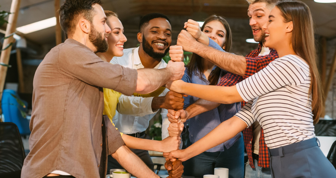 Photo of people teambuilding by creating a tower with their fists. 