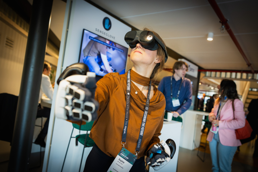 A woman wearing a VR headset and special gloves, seems to explore something.