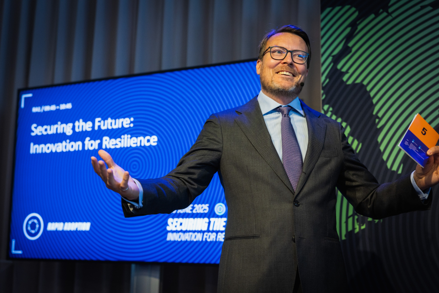 A man in a suit speaks enthusiastically at a conference.