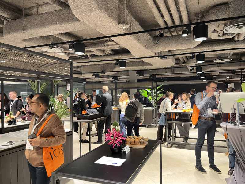 People in a modern space with food and plants at a networking event.