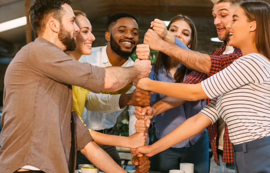 Photo of people teambuilding by creating a tower with their fists. 