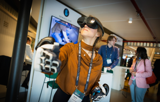 A woman wearing a VR headset and special gloves, seems to explore something.