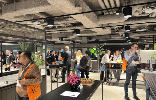 People in a modern space with food and plants at a networking event.