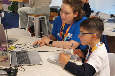 A woman and a boy are working together at a laptop.