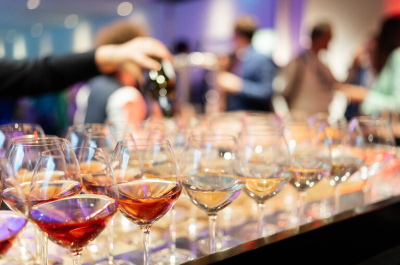 Row of various wine and water glasses with a hand pouring from a bottle