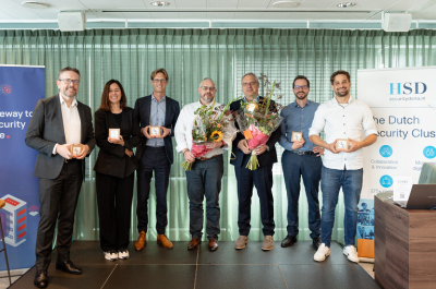 Group of people posing with flowers and awards during an event in The Hague