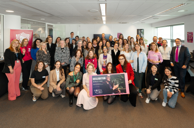A large group of women poses together with a sign for the camera.