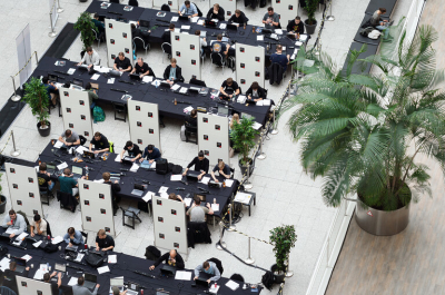 People at desks in a large workspace with plants