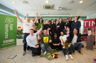 A group of people poses joyfully with flowers in an indoor setting.