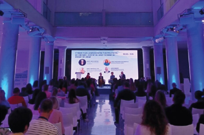 A panel discussion with a speaker and audience in a hall.