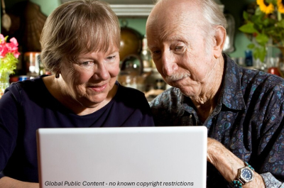 An older woman and man are looking at a laptop together.