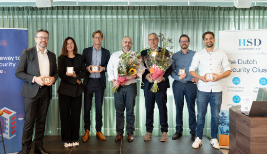 Group of people posing with flowers and awards during an event in The Hague