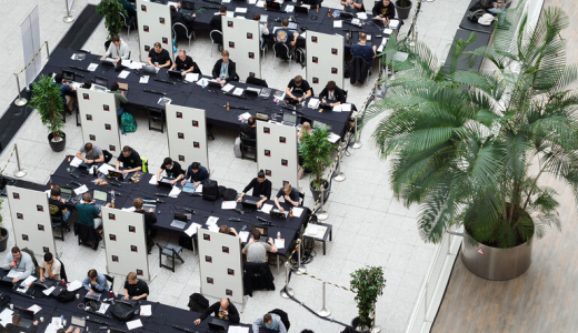 People at desks in a large workspace with plants