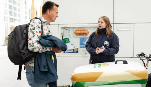 A man in a colorful jacket talks to a woman in a dark blue jacket in The Hague.