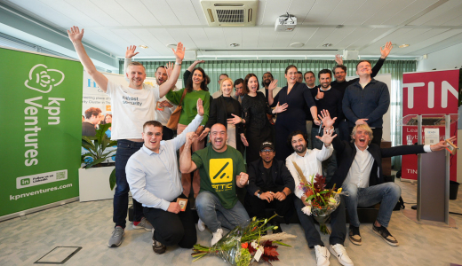 A group of people poses joyfully with flowers in an indoor setting.