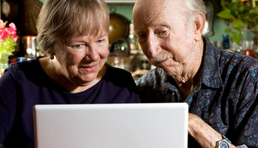 An older woman and man are looking at a laptop together.