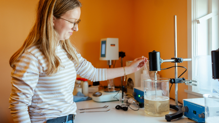 Een vrouw in een laboratorium mengt een vloeistof met een apparaat.