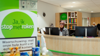 Medewerker achter een balie in een kantoor voor roken stop ondersteuning.