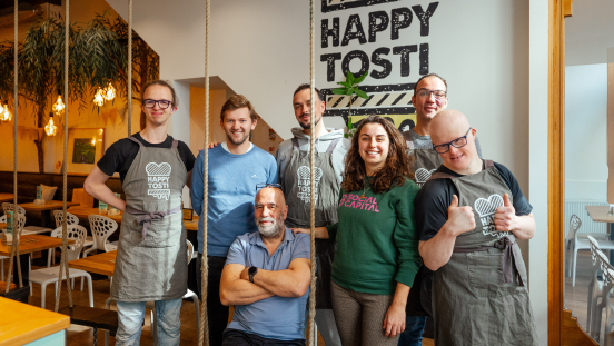 Zeven medewerkers van Happy Tosti poseren samen.