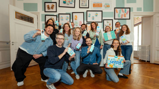 Een diverse groep mensen poseert met melkproducten in een kamer.