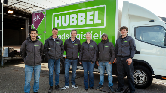 Zes medewerkers staan voor een groene Hubbels vrachtwagen.