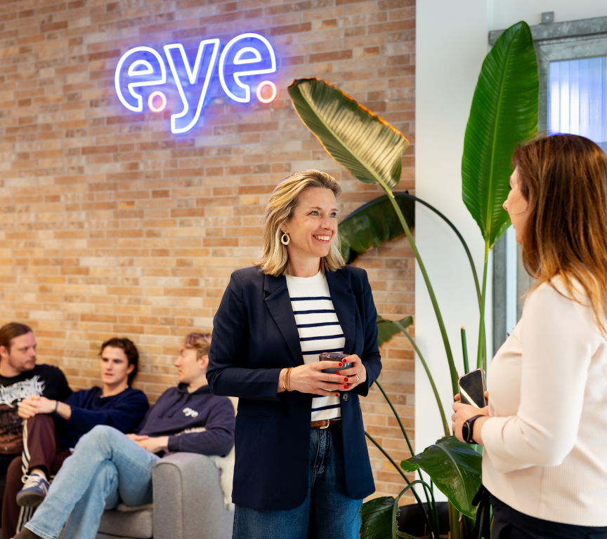Twee vrouwen in gesprek in een moderne omgeving met planten.
