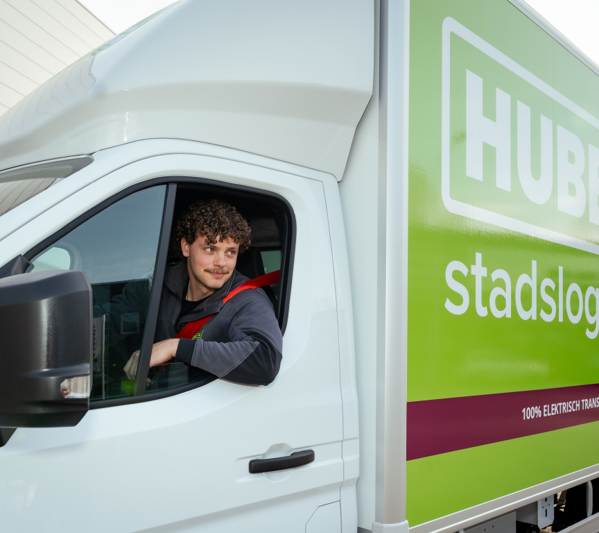 Jongeman met krullen zit in een elektrische vrachtwagen.