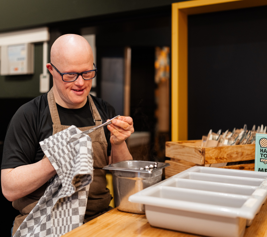 Man met een bril en schort, bezig met koken