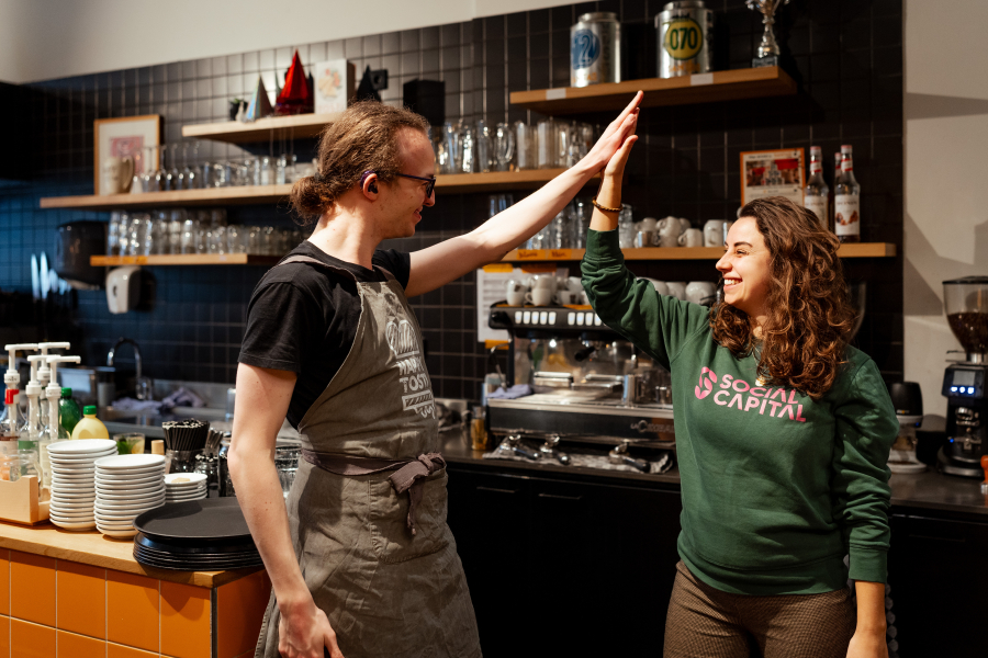 Twee mensen geven elkaar een hoge vijf in een café.