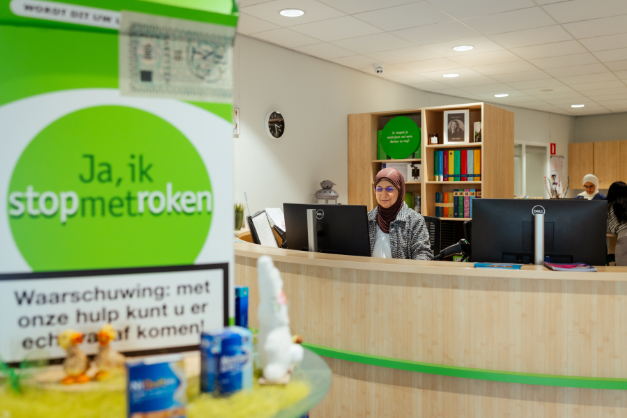 Medewerker achter een balie in een kantoor voor roken stop ondersteuning.