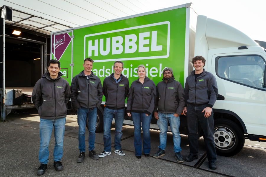 Zes medewerkers staan voor een groene Hubbels vrachtwagen.