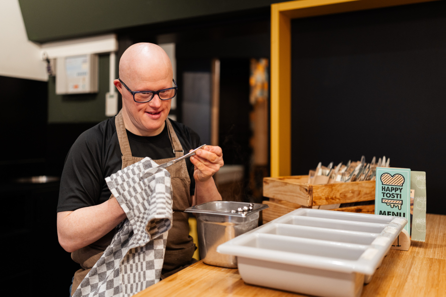 Man met een bril en schort, bezig met koken
