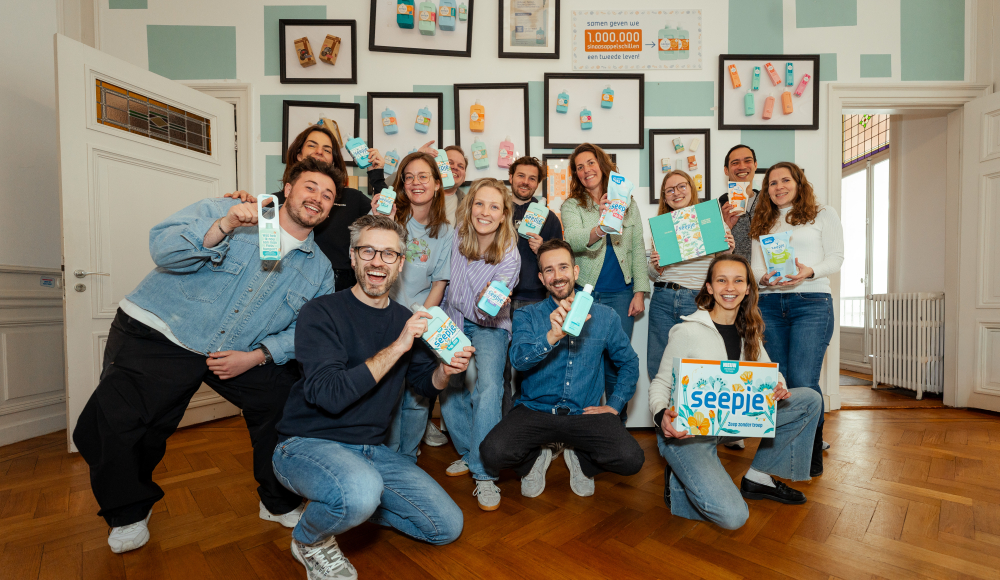 Een diverse groep mensen poseert met melkproducten in een kamer.
