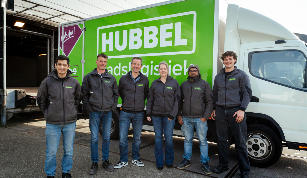 Zes medewerkers staan voor een groene Hubbels vrachtwagen.