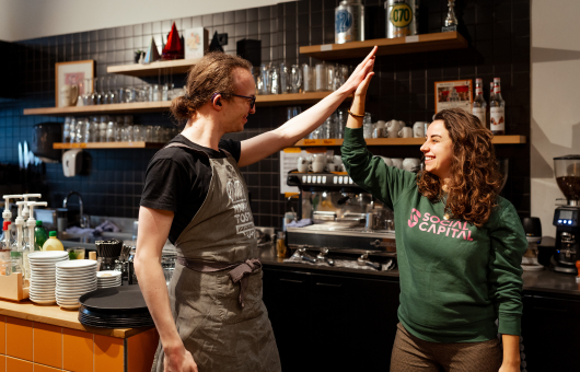 Twee mensen geven elkaar een hoge vijf in een café.