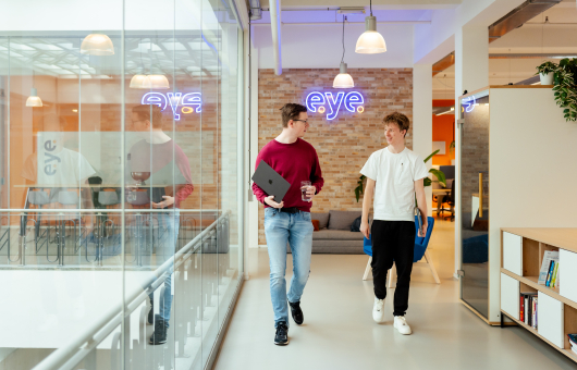 Twee mannen in casual kleding wandelen door een kantoor.
