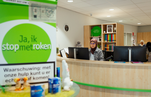 Medewerker achter een balie in een kantoor voor roken stop ondersteuning.