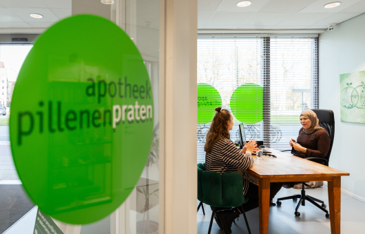 Twee vrouwen in gesprek in een apotheek.