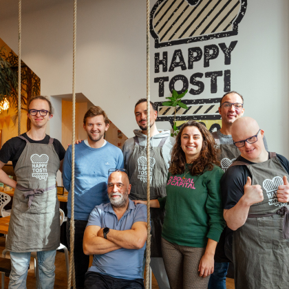 Zeven medewerkers van Happy Tosti poseren samen.