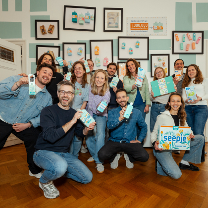 Een diverse groep mensen poseert met melkproducten in een kamer.