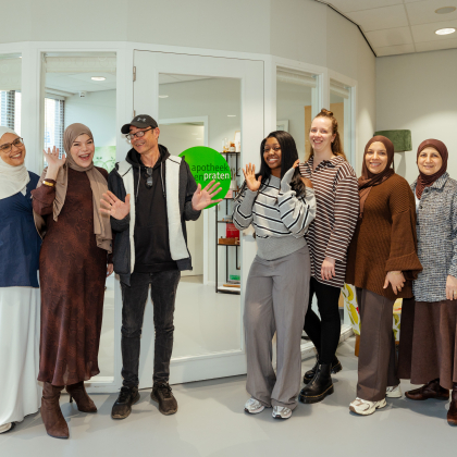 Acht mensen staan lachend voor een apotheekinterieur.