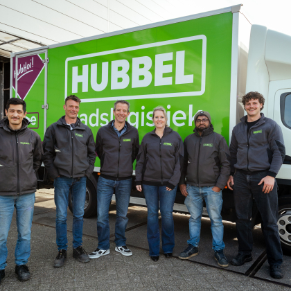 Zes medewerkers staan voor een groene Hubbels vrachtwagen.