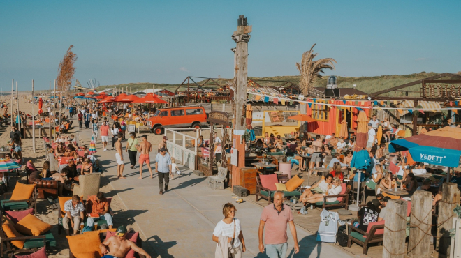 Busy beach promenade with people, chairs, and a vibrant atmosphere.