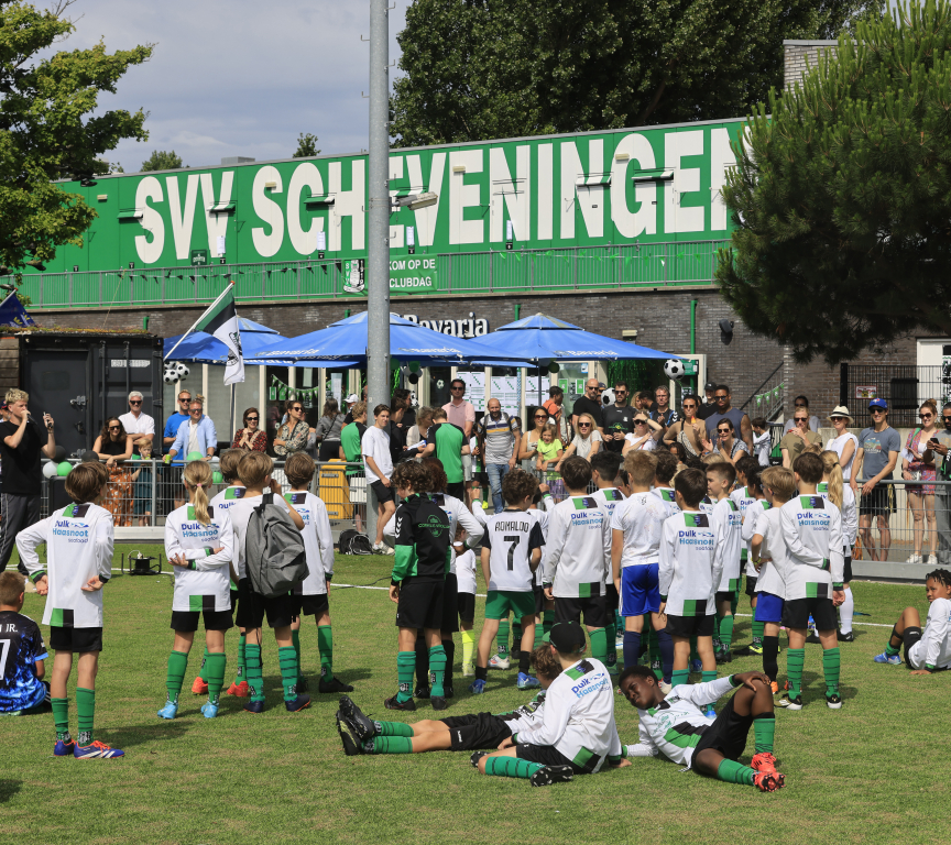 Children in green and white kits training on a football field.
