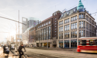 Facade of University Campus Spui with cyclists and tram in the foreground.