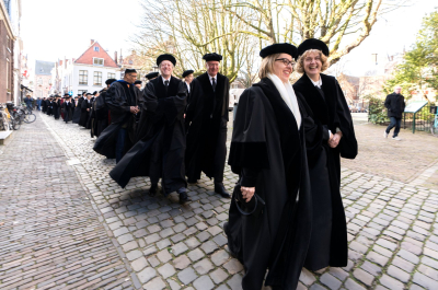 Group of academics in traditional attire walking down a street.