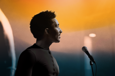 A man stands sideways at a microphone, singing.