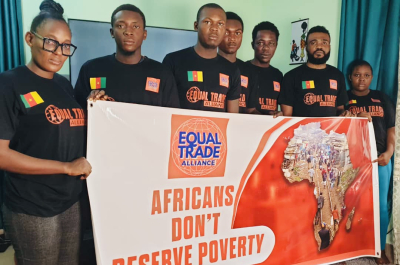 Seven people in black shirts holding a poster reading 'Africans don’t deserve poverty'.