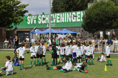 Children in green and white kits training on a football field.