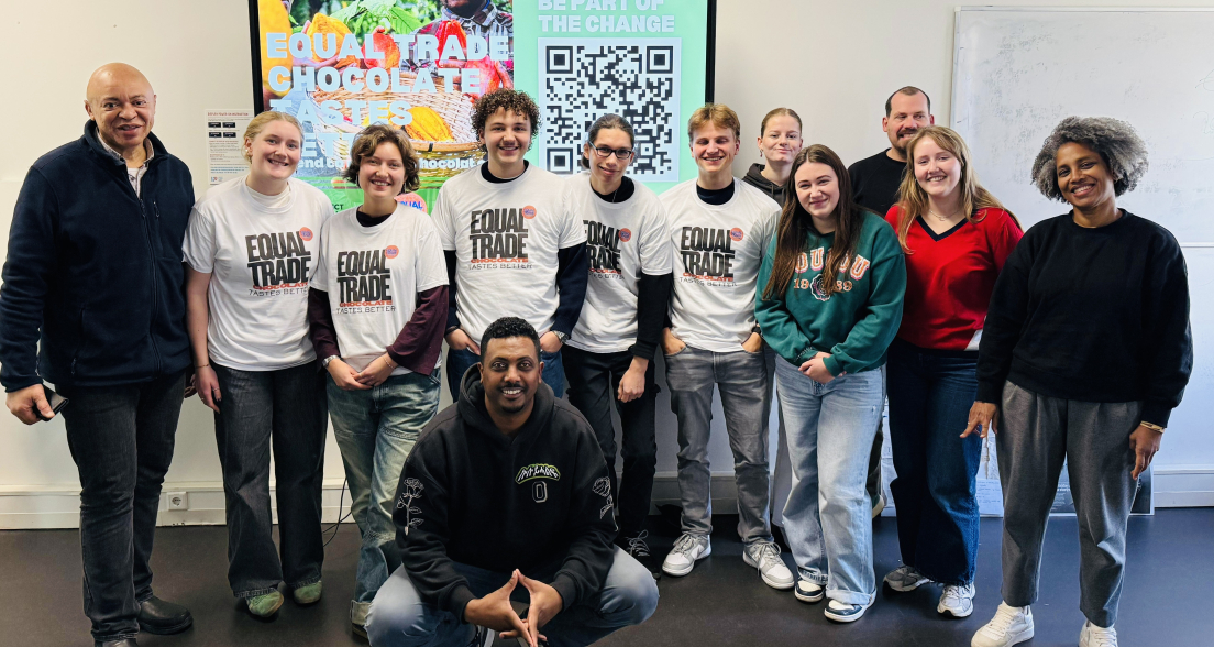 A diverse group of people wearing Equal Trade t-shirts stands in front of a screen with information.
